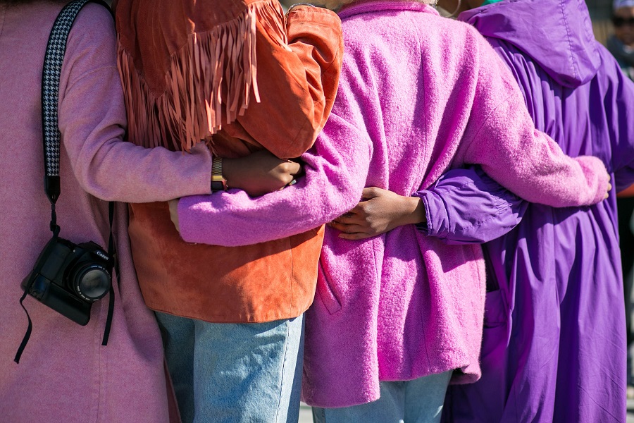 women standing together with their arms around each other