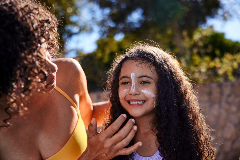 woman helping child put sunscreen on face